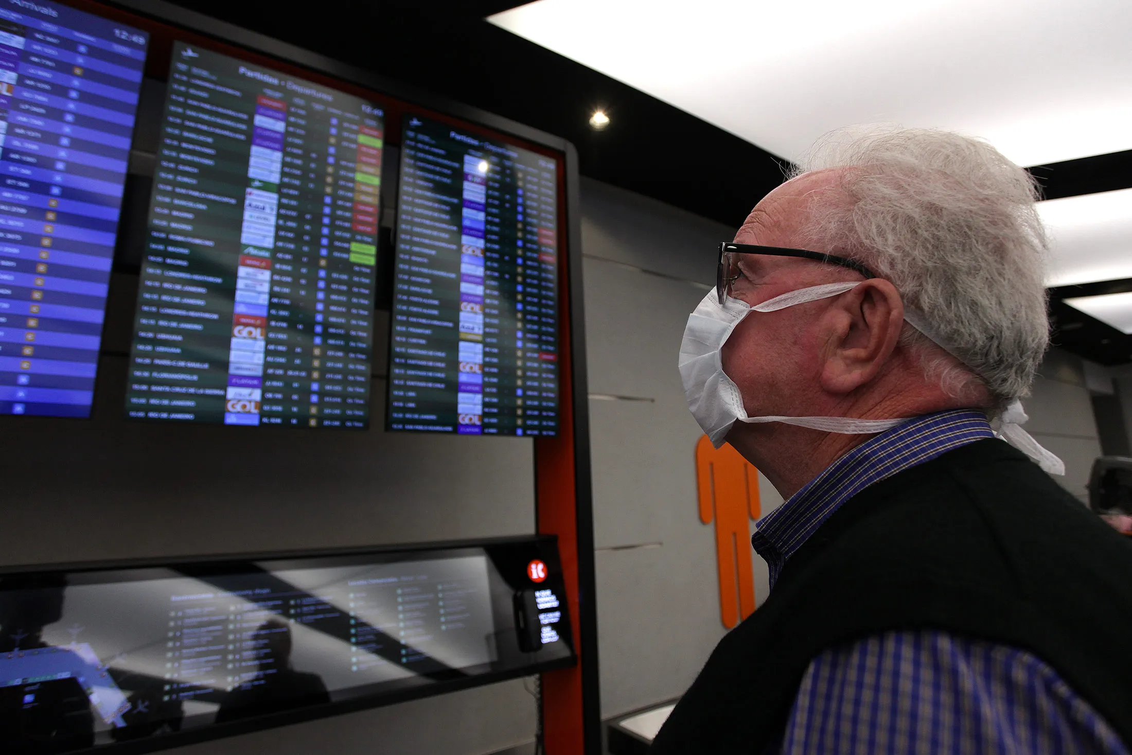 A traveler wearing protective mask looks at an information board at Ezeiza International Airport&nbsp;in Buenos Aires, on March 16.
