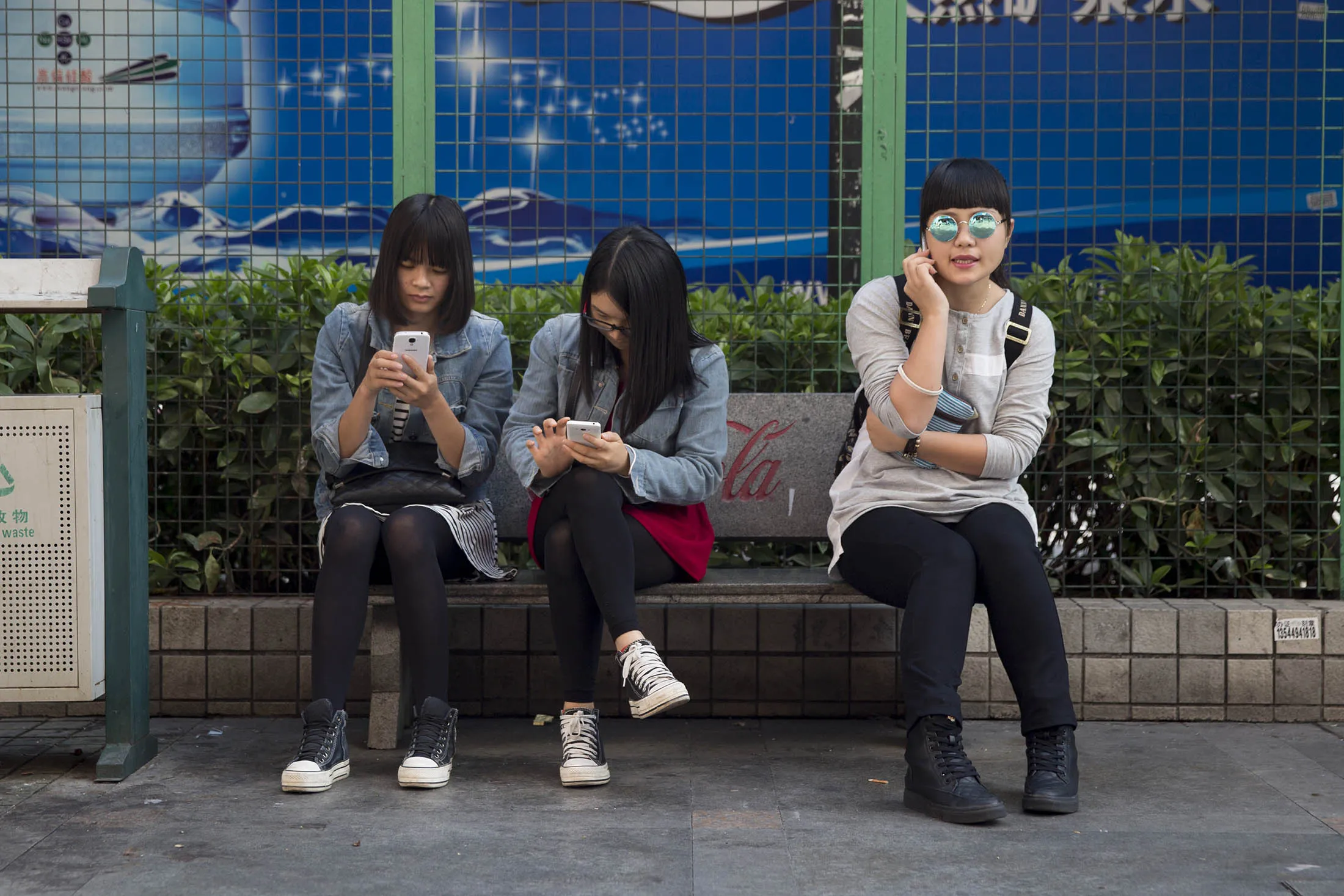 Women use mobile phones while sitting on a bench in the Gongbei district of Zhuhai, Guangdong province, China.
