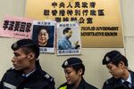 Police walk past missing person notices of Gui Minhai, left, one of five missing booksellers from the Mighty Current publishing house. Photographer: Anthony Wallace/AFP/Getty Images
