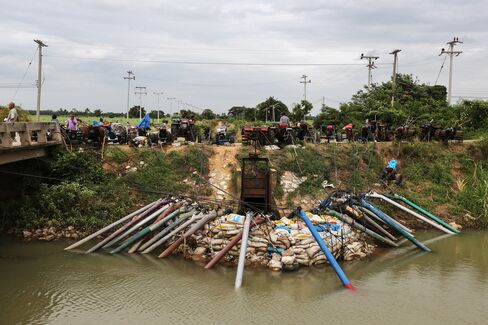 Farmers stand by their water pumps at the Makhamtao Uthong irrigation canal in Praek Sriracha, Chainat province, on June 22, 2015. Photographer: Dario Pignatelli/Bloomberg
