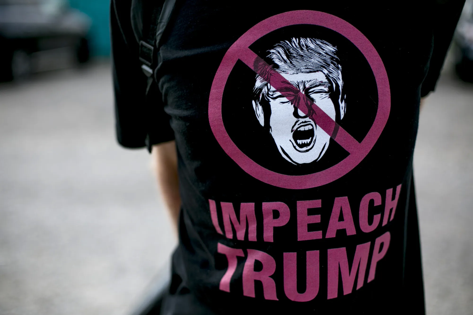 A person wears an 'Impeach Trump' shirt.