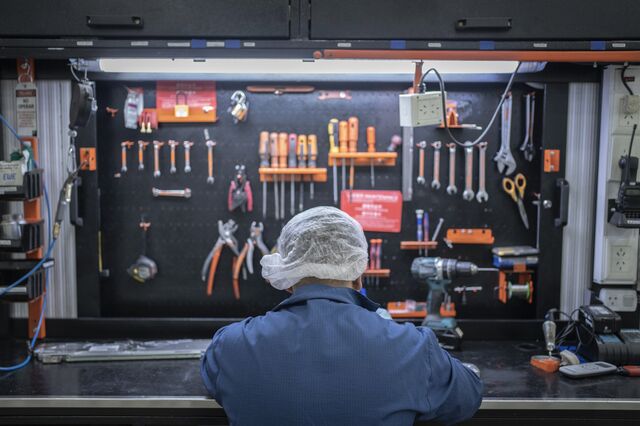 A worker assembles air conditioner parts. 