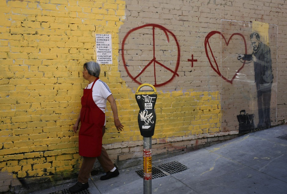 A woman passes a Banksy mural in San Francisco. 