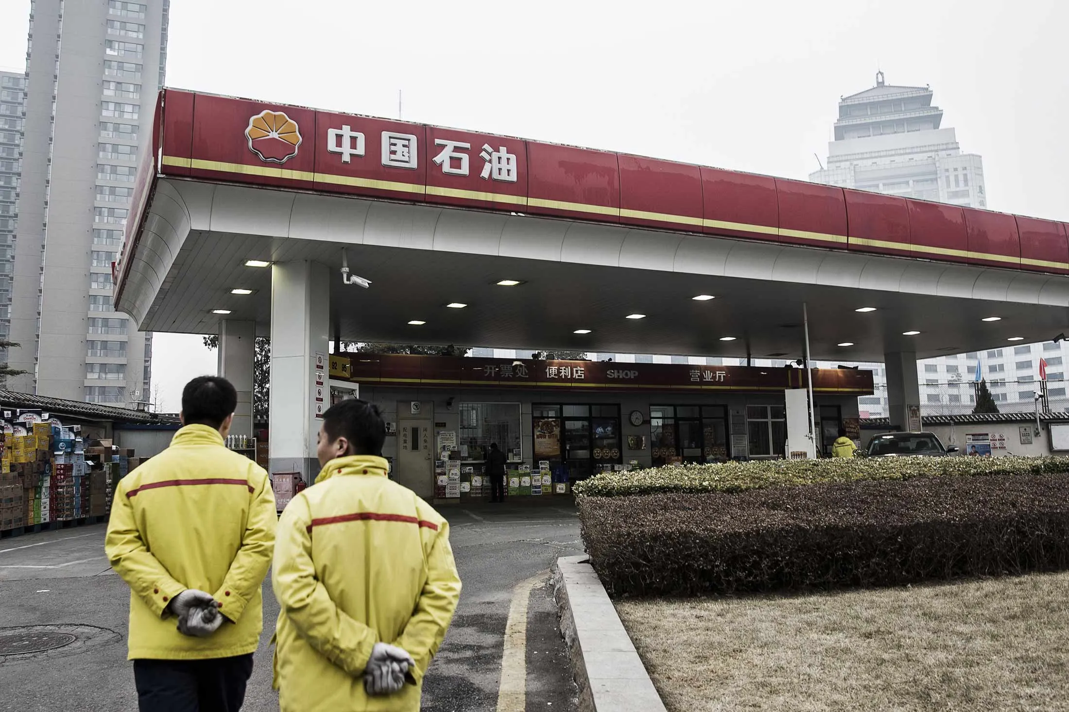 Employees stand at a PetroChina Co. gas station in Beijing, China, on Friday, March 4, 2016.
