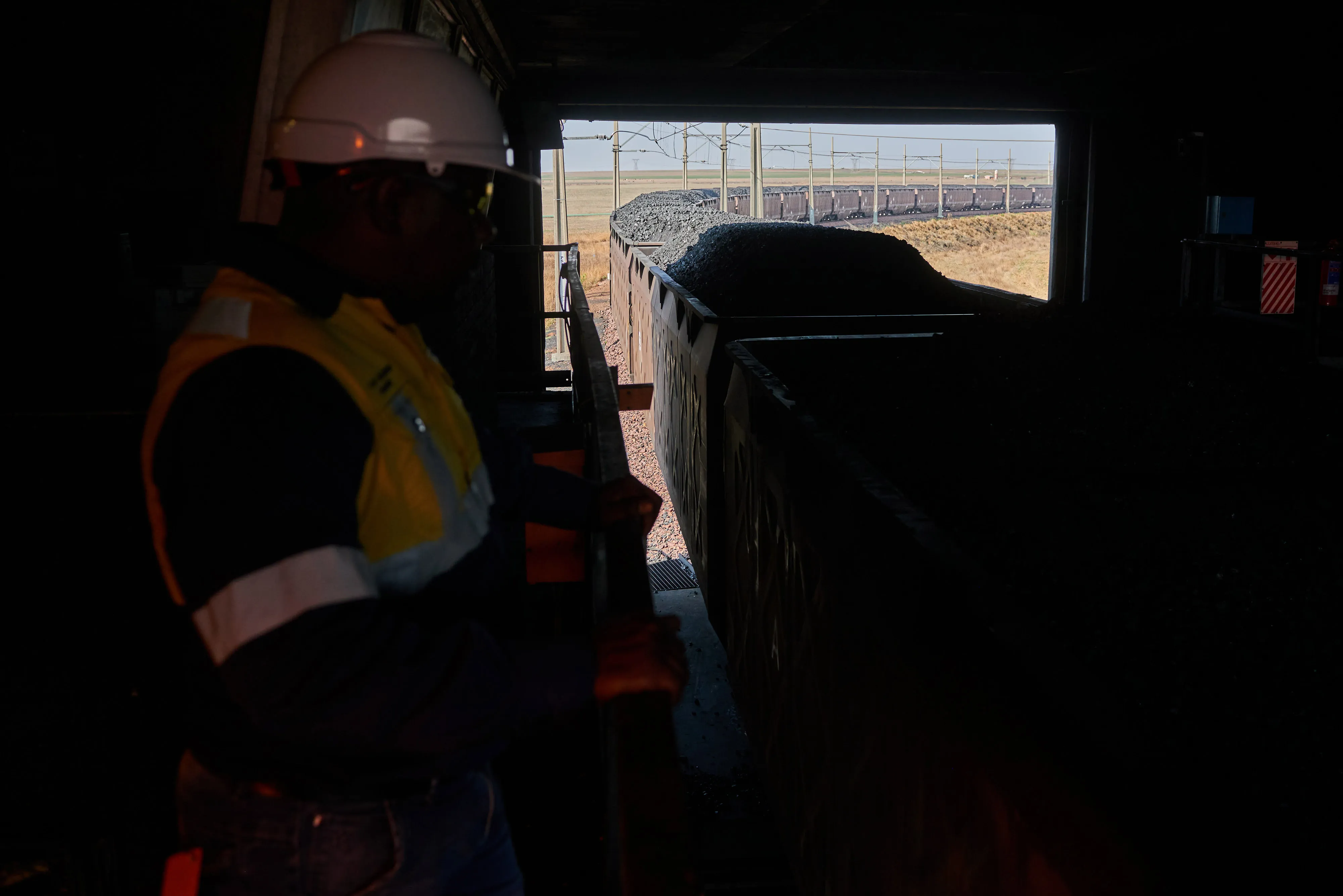 A worker monitors coal freight wagons at&nbsp;an open-cast coal mine&nbsp;in Mpumalanga, South Africa.
