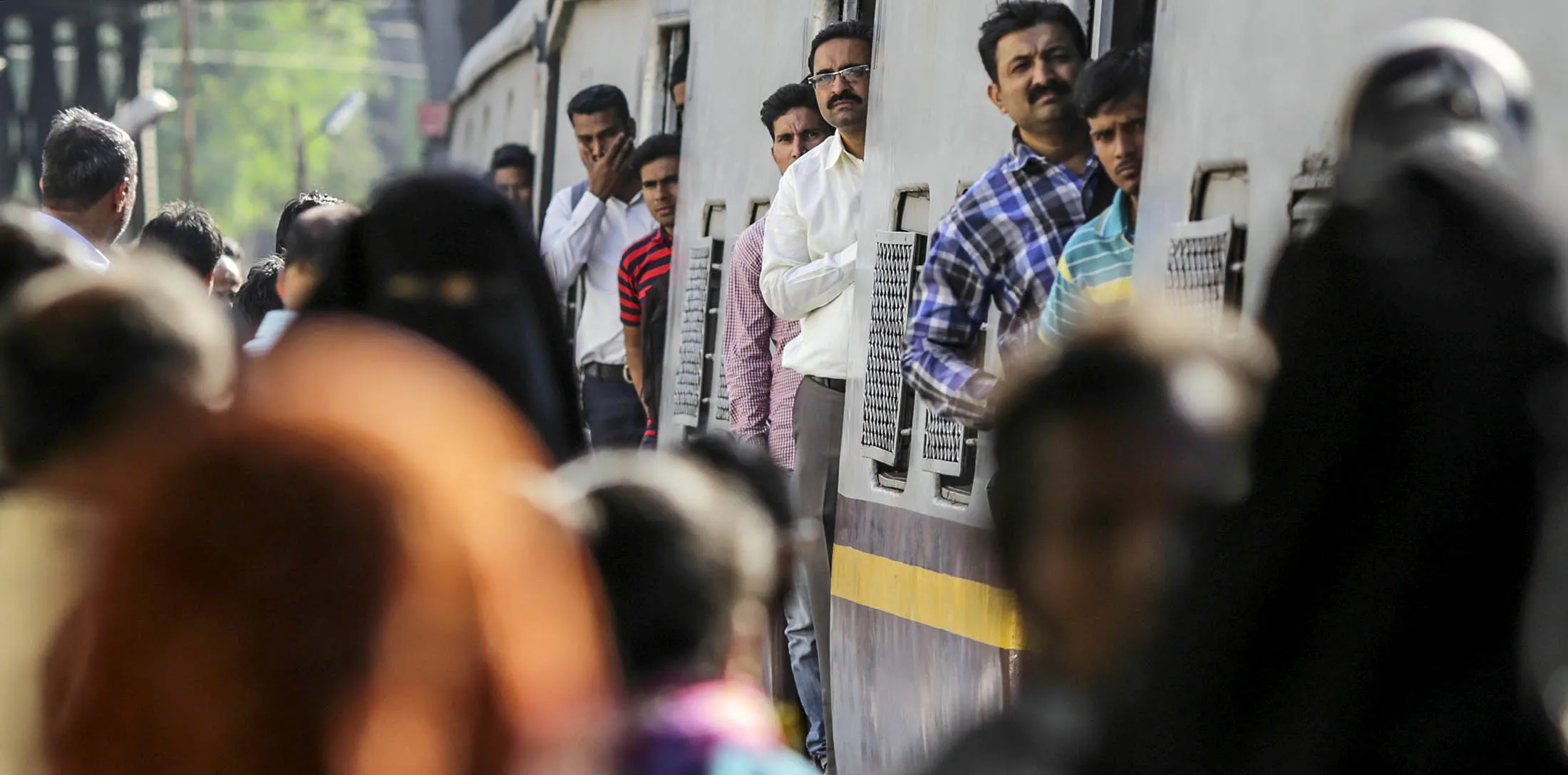 Commuters stand at the carriage doors of a train as it arrives at Mumbai Central Train Station in Mumbai, India, on Friday, Jan. 22, 2016. Global investors are keeping faith in India's rupee bonds, even as the currency inches toward the record low reached in 2013, saying the nation's finances have improved over the past 2 1/2 years.
