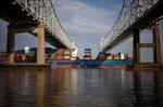 A container ship passes beneath the Crescent City Connection bridge near the Port of New Orleans.