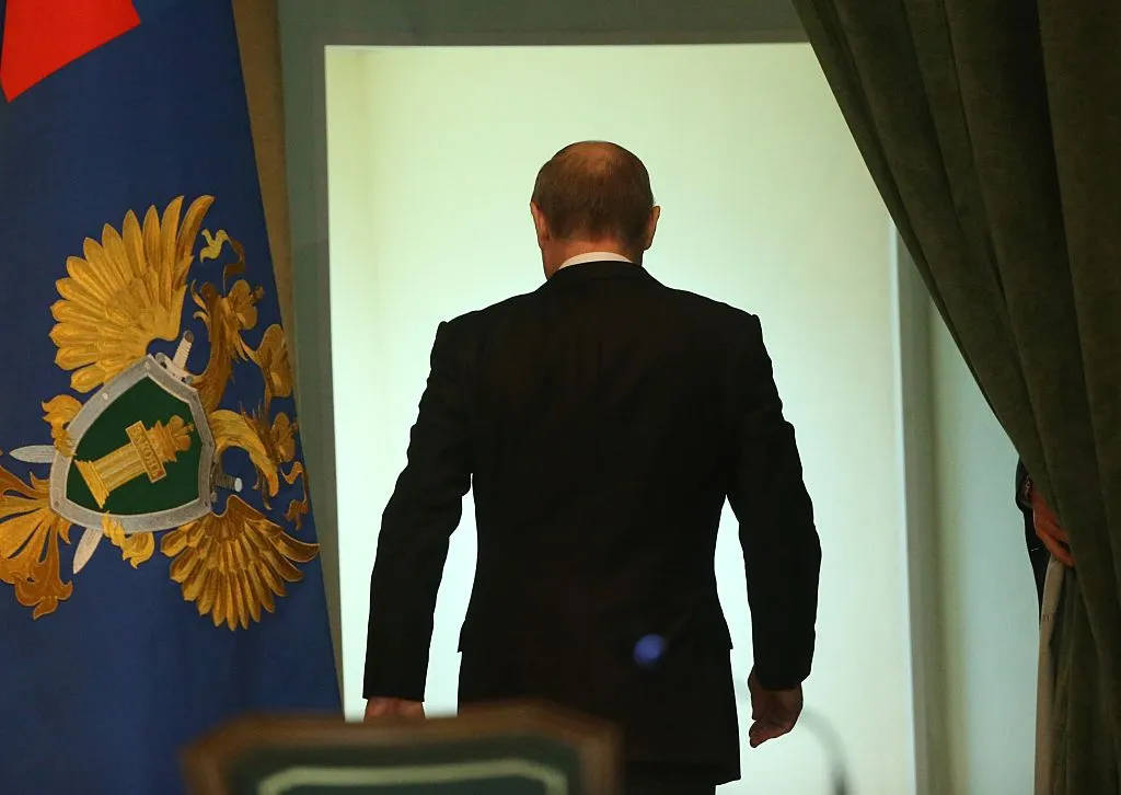 Turning his back.
