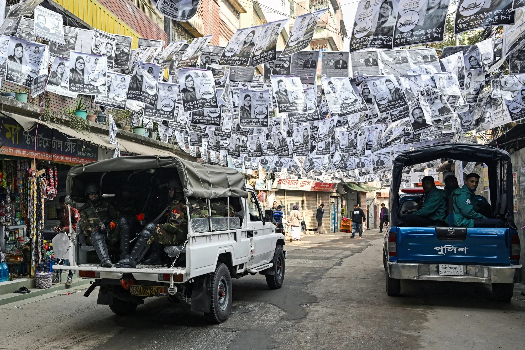 Security personnel patrol a street lined with election posters in Dhaka on Jan. 6.