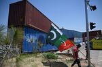 A supporter of Pakistan Tehreek-e-Insaf (PTI) party, carries flags next to containers stacked by the authorities to block the Red Zone ahead of the sit-in planned in Islamabad, Pakistan, on May 24.