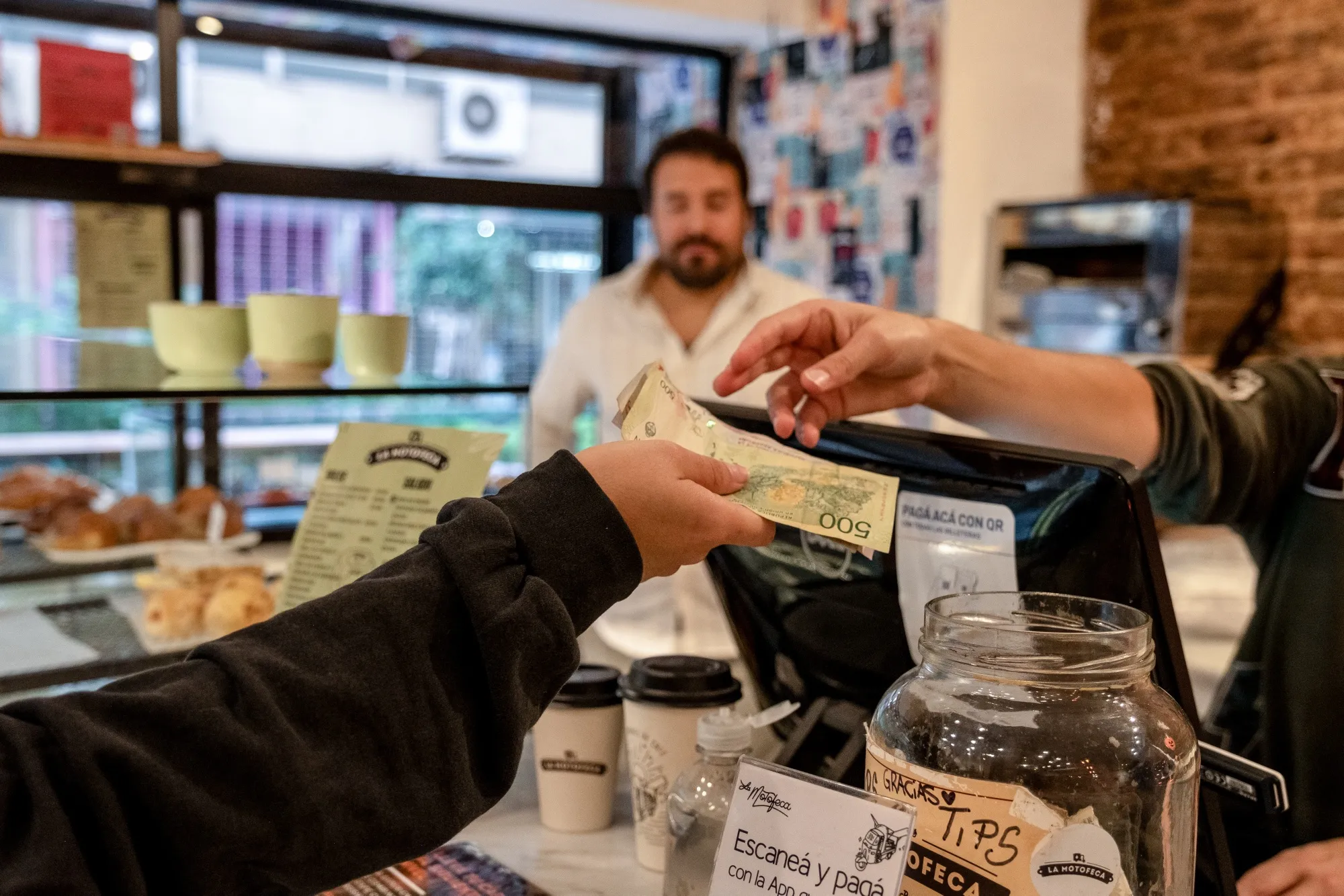 A customer pays with Argentine peso banknotes at a shop in Buenos Aires, Argentina.