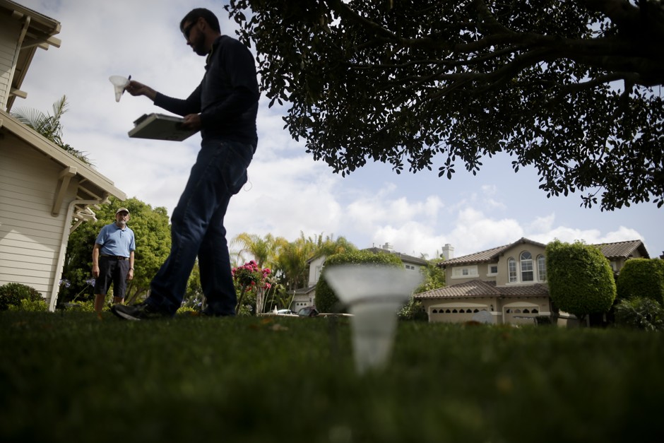Glen Peterson, left, looks on as Dan Denning, a water conservationist for the San Diego County Water Authority, checks sprinkler flow on his lawn in Carlsbad, California. 