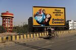 A rickshaw-puller travels past an Abuja Cements Ltd. billboard on a highway in Patna, Bihar, India.