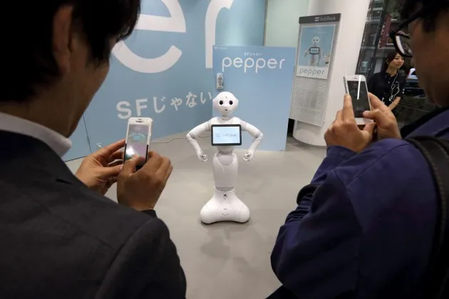 Customers interact with the humanoid robot 'Pepper', developed by SoftBank's Aldebaran Robotics unit