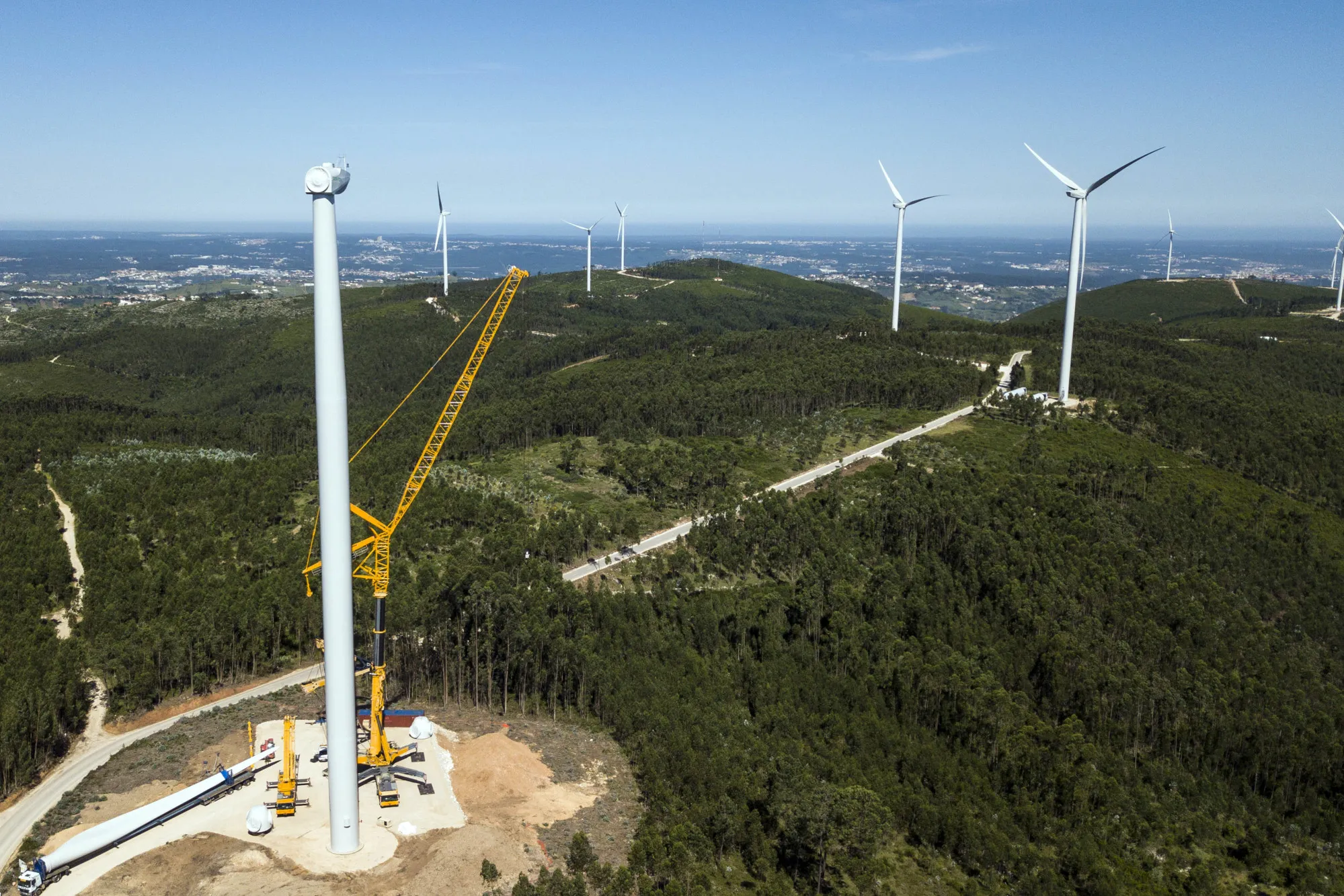Worker prepare to hoist a wind turbine propeller blade into position onto a tower in an energy park operated by EDP&nbsp;SA in Maunca, Portugal.