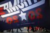 A campaign flag silhouettes attendees waiting in line to enter a rally with U.S. President Trump, not pictured, in Lexington, Kentucky in 2019.