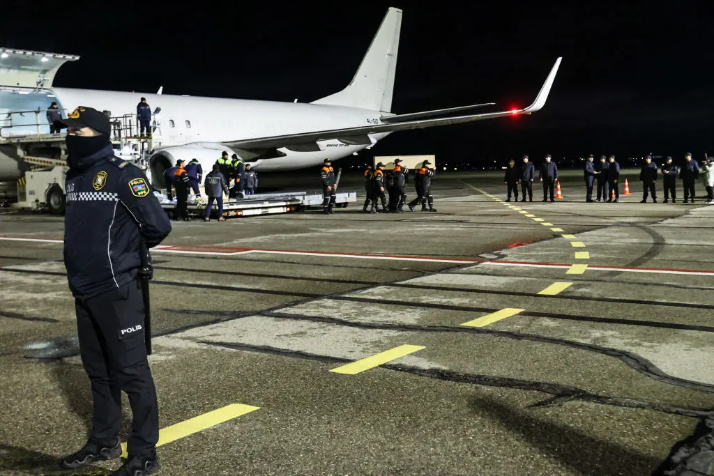 Workers carry a coffin with a body of a victim from a plane after the Azerbaijani Airlines crashed, near&nbsp;Aktau.