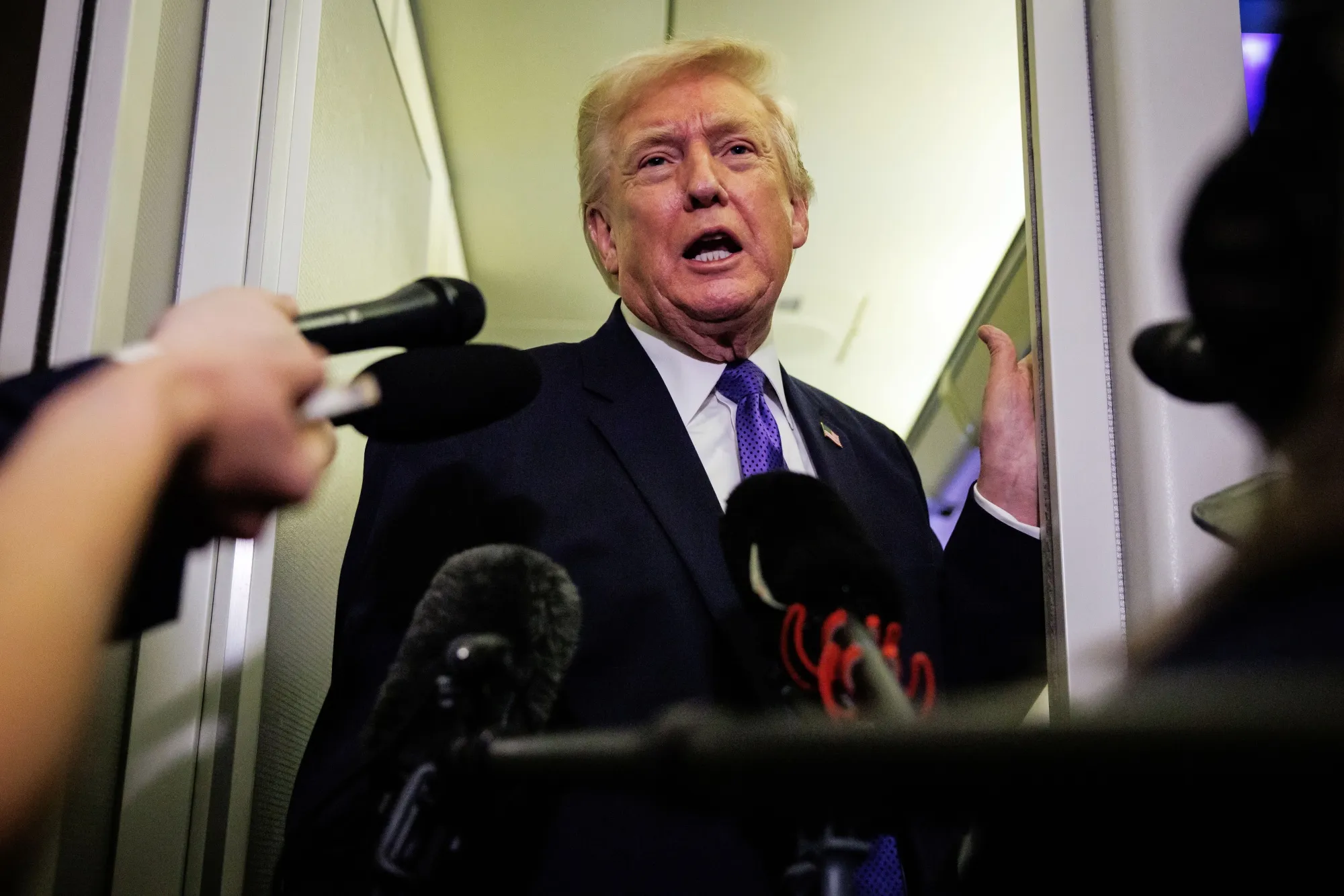 President Donald Trump speaks with reporters aboard Air Force One on Feb. 6 en route to Palm Beach, Florida.