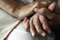 A nurse holds the hands of a person suff