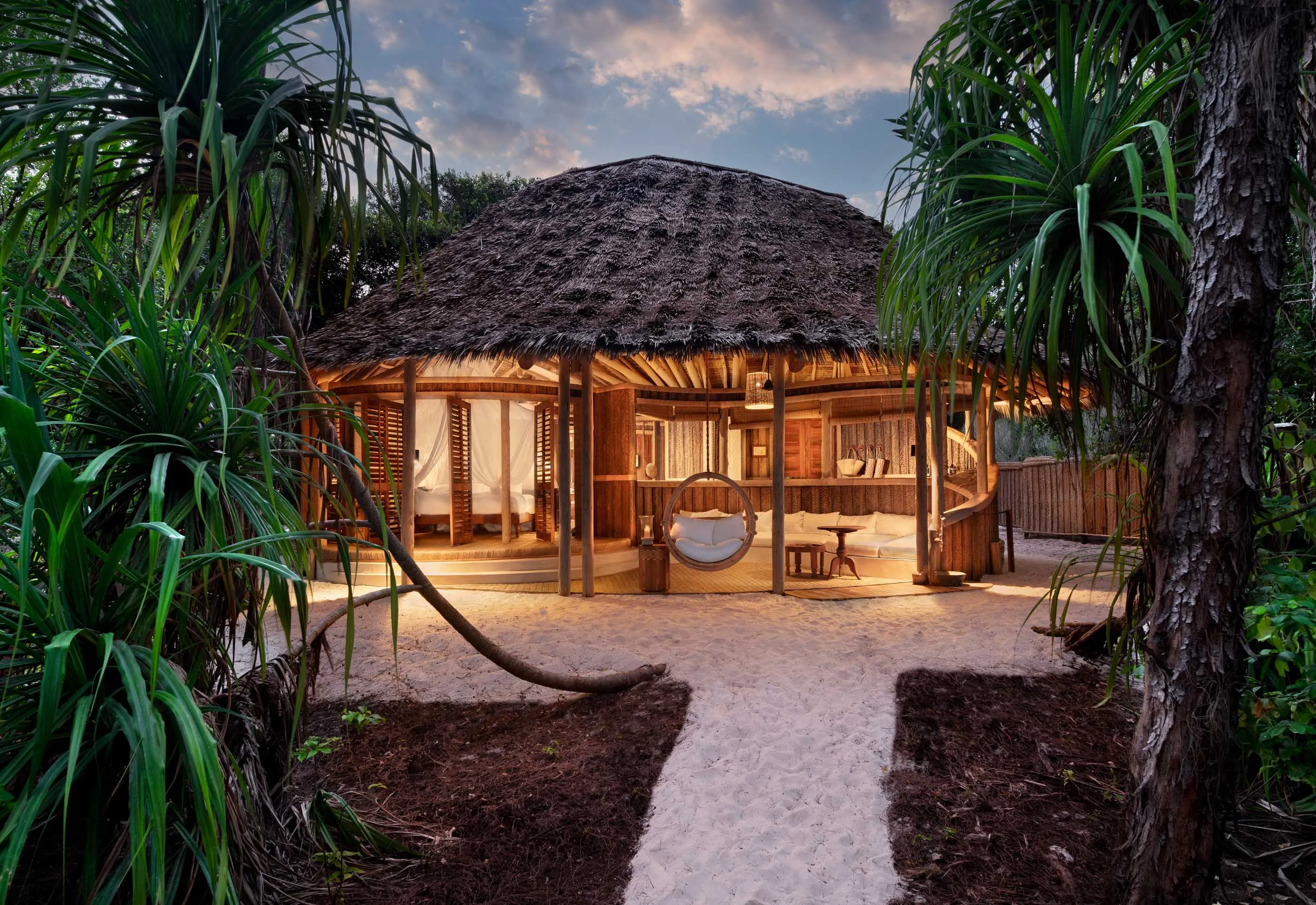 A thatched roof beach bungalow at AndBeyond's Mnemba Island, a private beach resort off the coast of Zanzibar.
