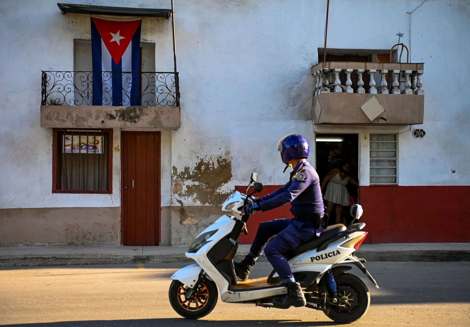 A police officer rides a motorbike in front of a house in Havana.