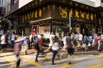 Pedestrians cross a road in front of a Lao Feng Xiang Co. jewelry store in the Mong Kok district of Hong Kong, China, on Sunday, Sept. 20, 2015. Little known outside mainland China, 167-year-old jeweler Lao Feng Xiang Co., is part of a wave of Chinese retailers that are inverting Hong Kong's high-end shopping model.
