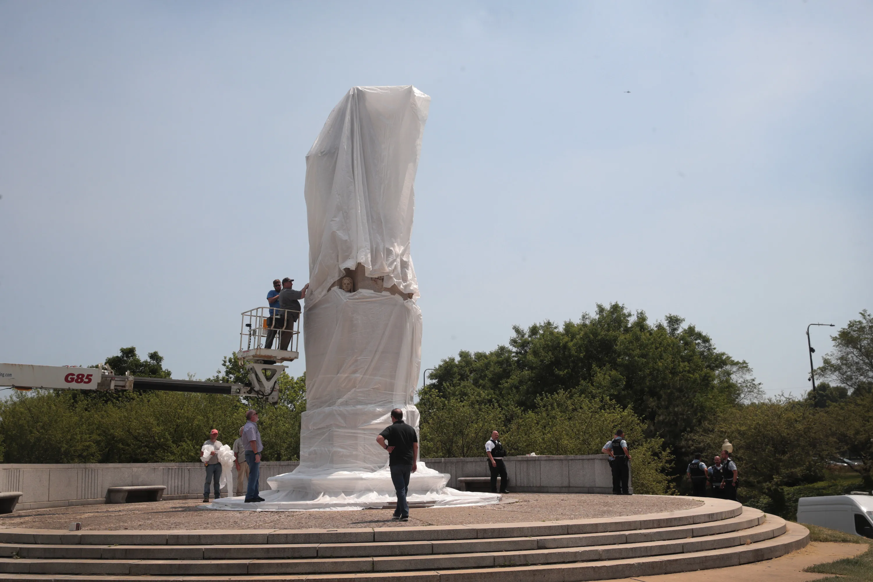 Workers cover a statue of Christopher Columbus in Chicago before the start of a Juneteenth march on June 19, 2020. The memorial was later removed.&nbsp;
