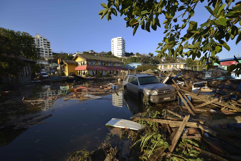 A car is surrounded by debris in a flooded street after an earthquake-triggered tsunami hit Concon, Chile, Thursday, September 17, 2015.