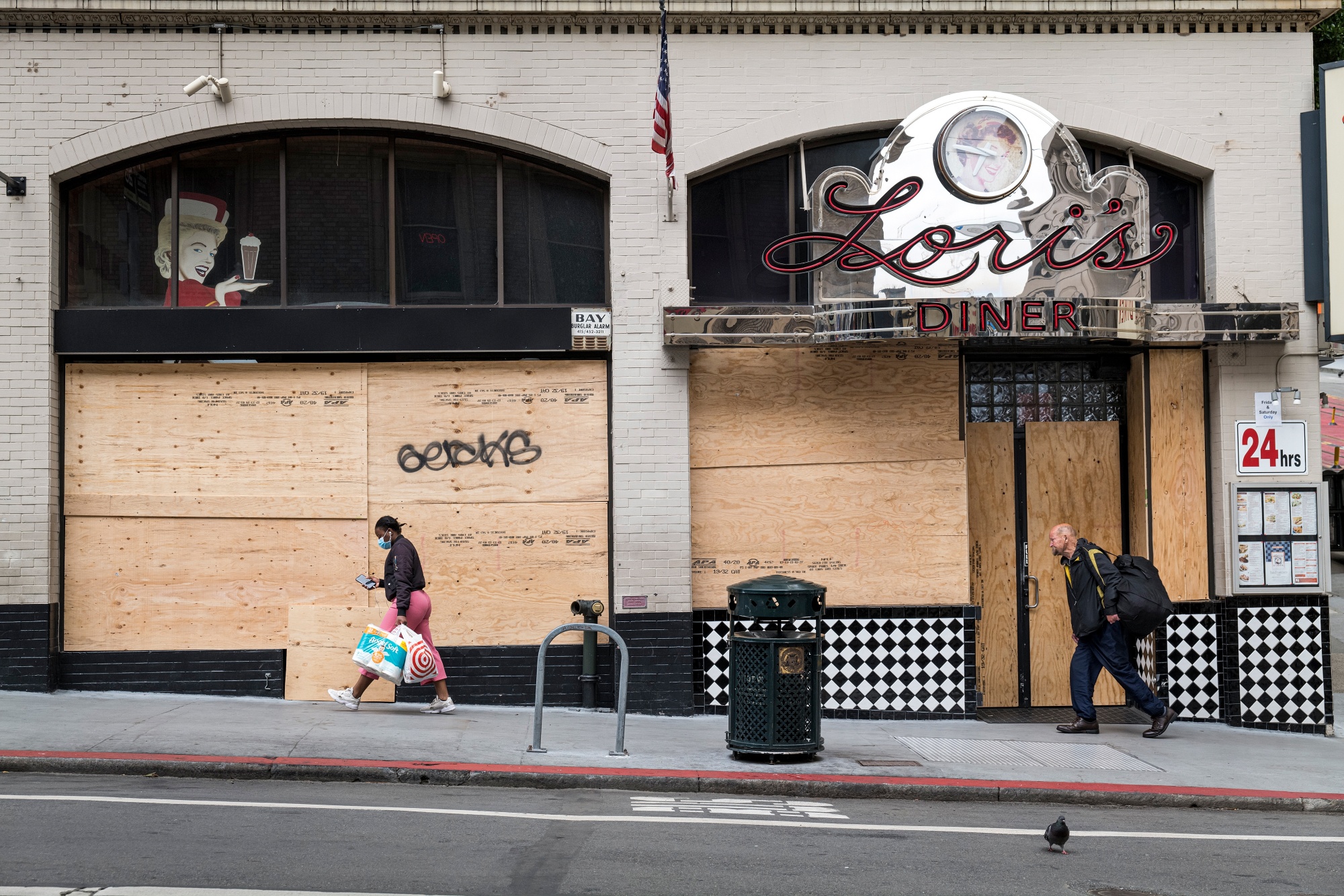 Pedestrians walk past a boarded up Lori's Diner in San Francisco, California, U.S.