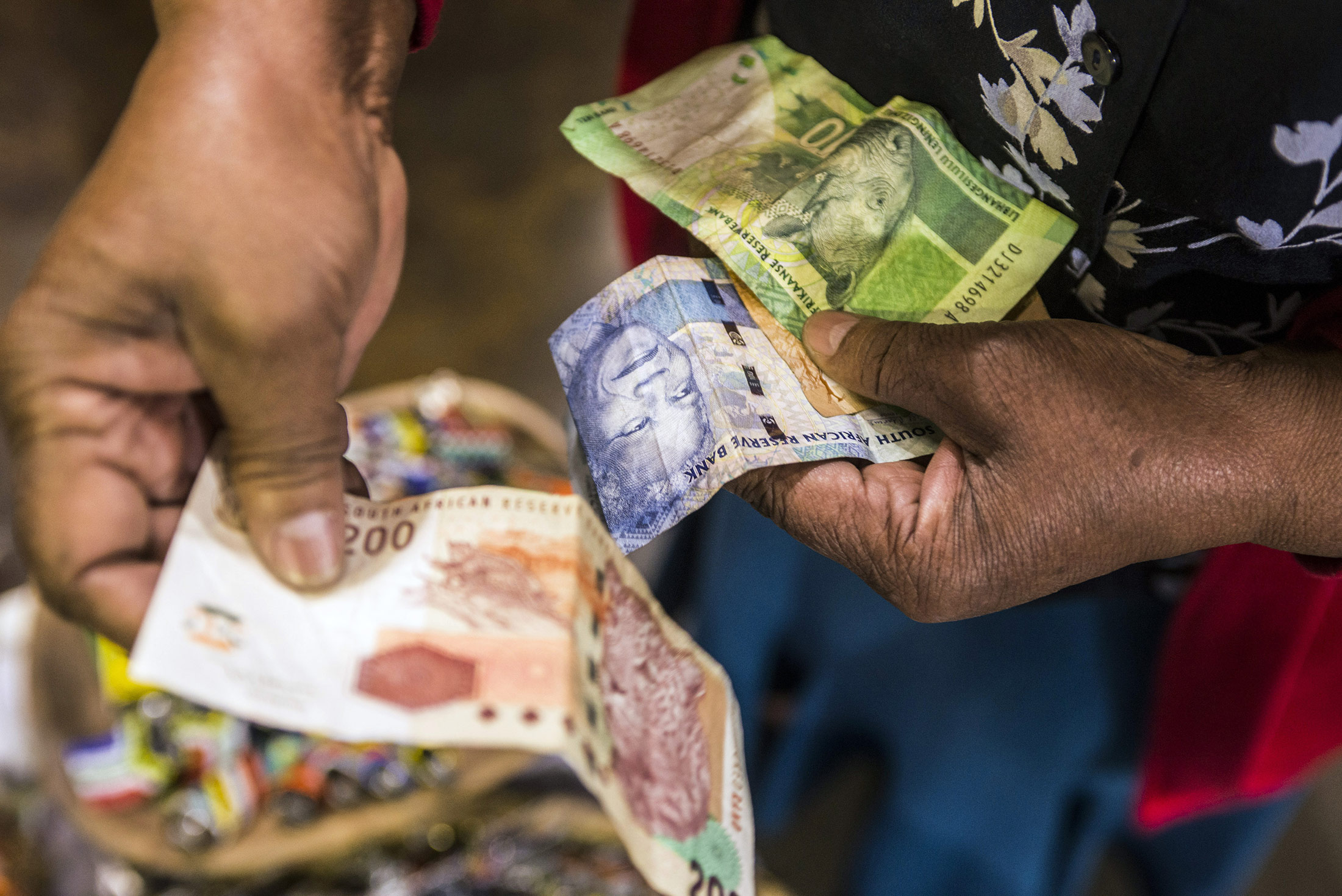 A vendor counts out rand banknotes while working in an African craft market in the Rosebank district of Johannesburg, South Africa, on Wednesday, Aug. 26, 2015. More than four years of currency declines -- to a fresh low this week -- aren't enough to offset electricity shortages, strikes and slowing demand from Asia and Europe that are pushing the economy to the brink of recession.

