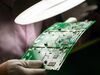 An employee in protective clothing inspects a circuit board in the Philippines.