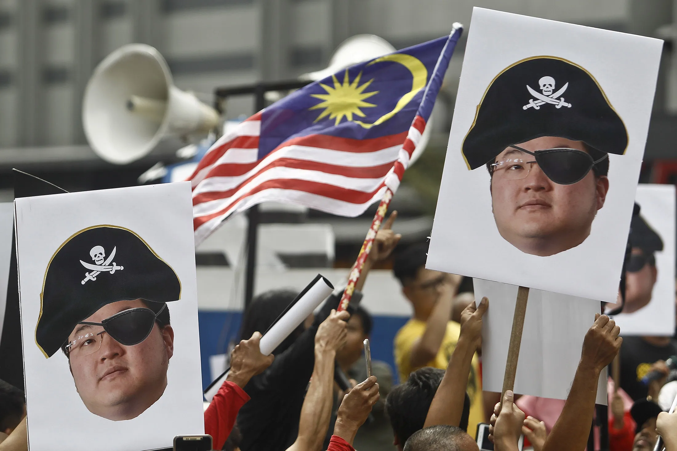 Protesters hold portraits of Jho Low illustrated as a pirate.