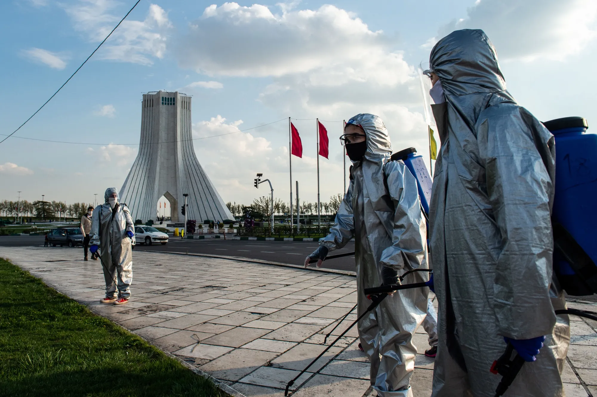 Volunteers use sprays to disinfect the ground around Azadi Square in Tehran on March 27.
