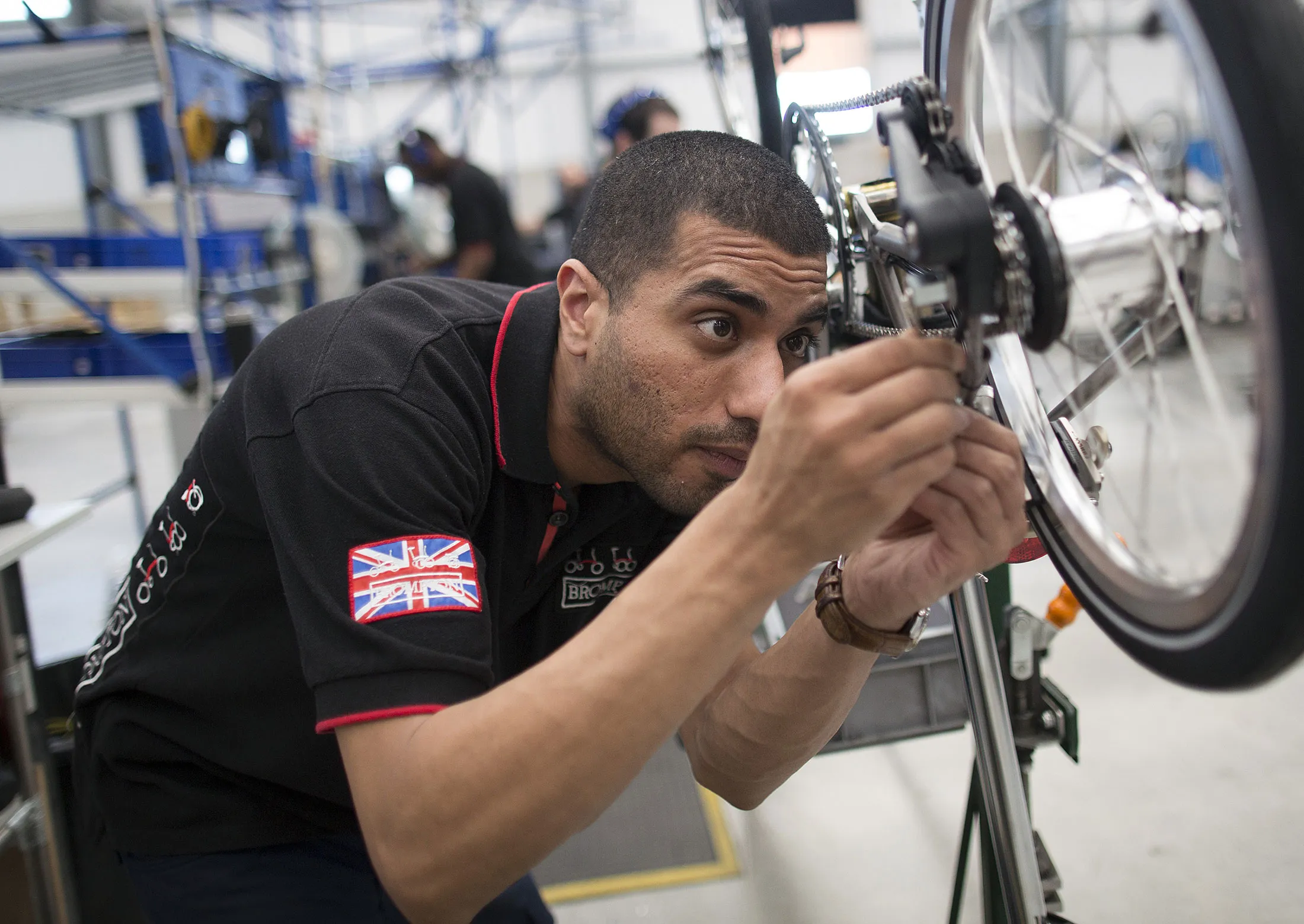 An employee adjusts an internal hub gear on a Brompton folding bicycle in the assembly area inside the Brompton Bicycle Ltd. factory in London, U.K., on Friday, May 13, 2016. The Brompton was created in 1975 by Andrew Ritchie, a Cambridge-trained engineer.
