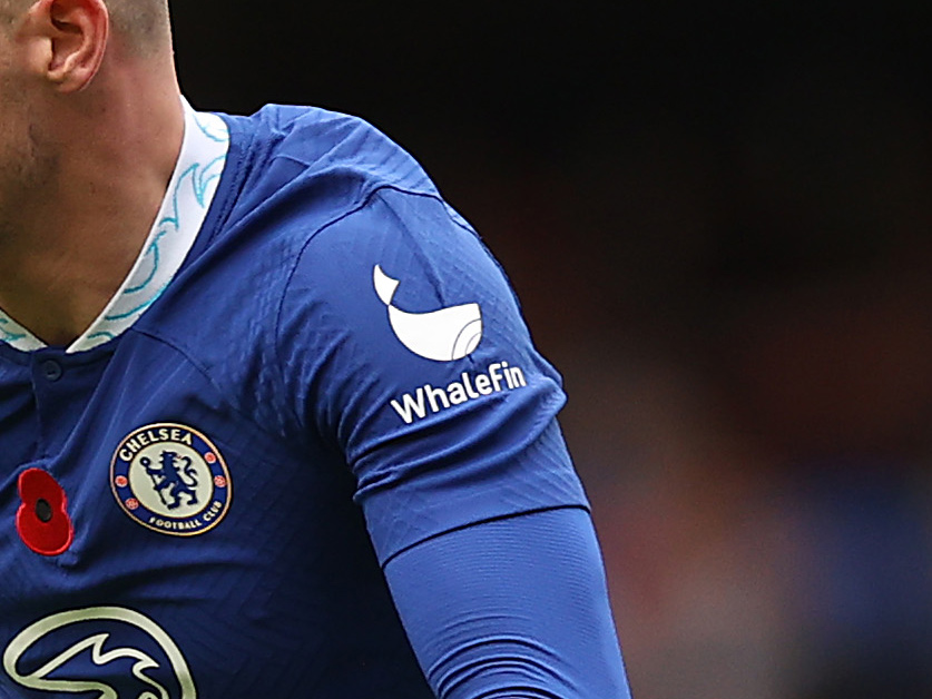 Amber’s WhaleFin trading platform logo on the sleeve of a Chelsea jersey.