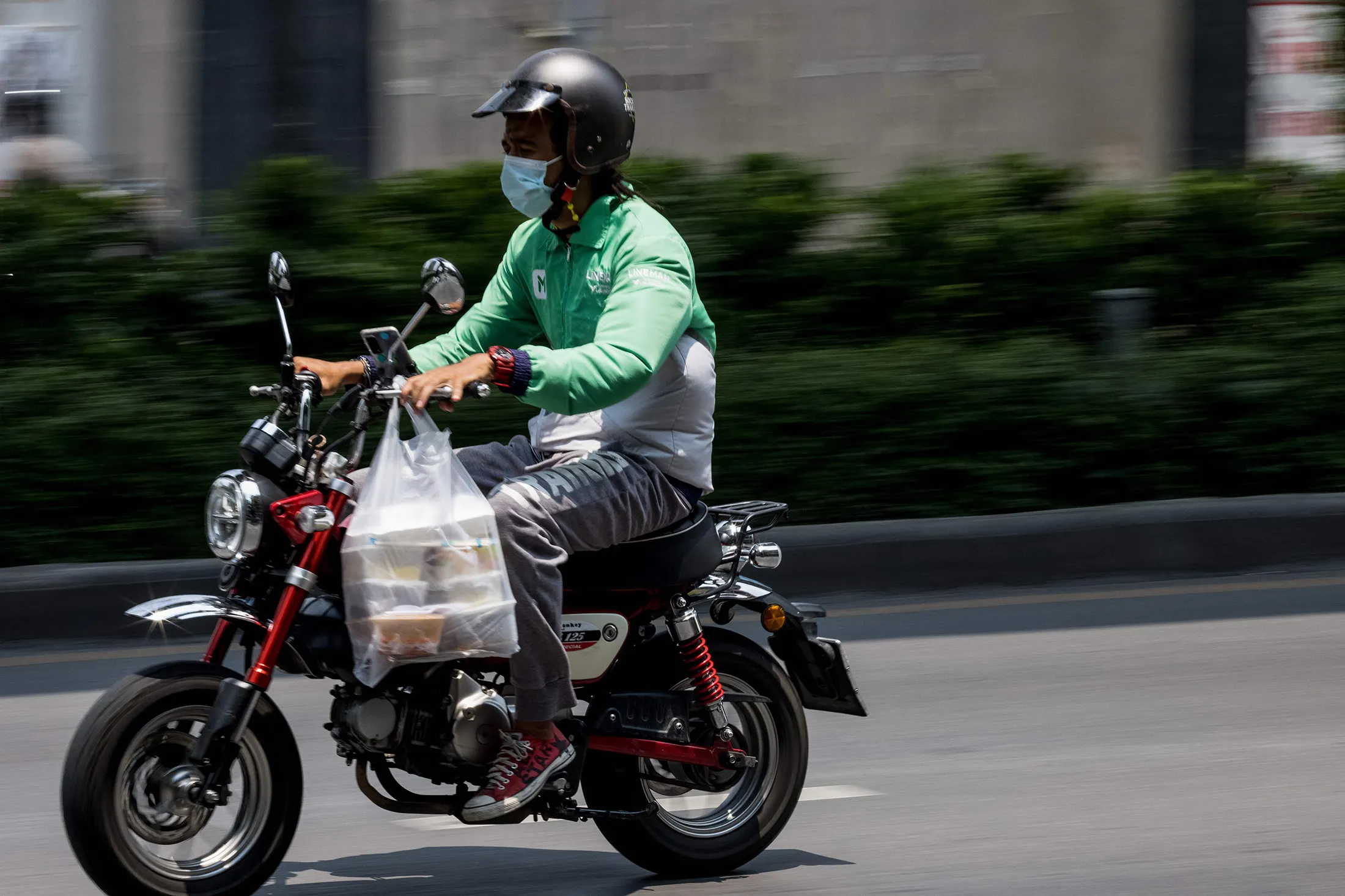 A Line Man food delivery driver carries an order in Bangkok. 