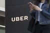 A pedestrian checks her mobile phone in front of the Uber Technologies Inc., headquarters in San Francisco, California, U.S.