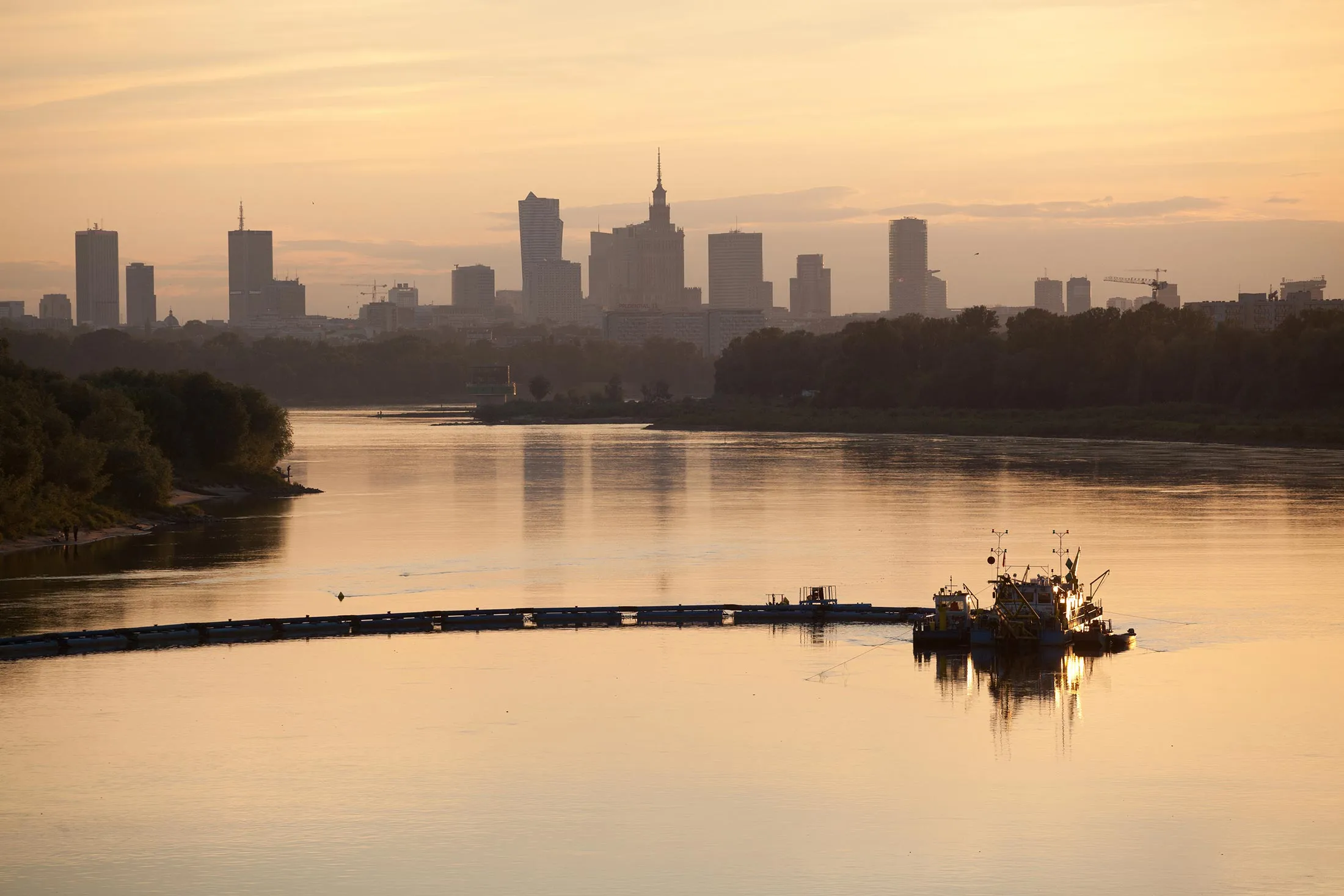 A dredger works on the River Vistula beyond the city skyline in Warsaw, Poland.
