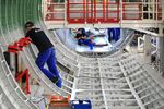 Employees work inside a center fuselage section of an Airbus A320 passenger aircraft inside the Airbus SE A320 family assembly line hangar in Hamburg, Germany.