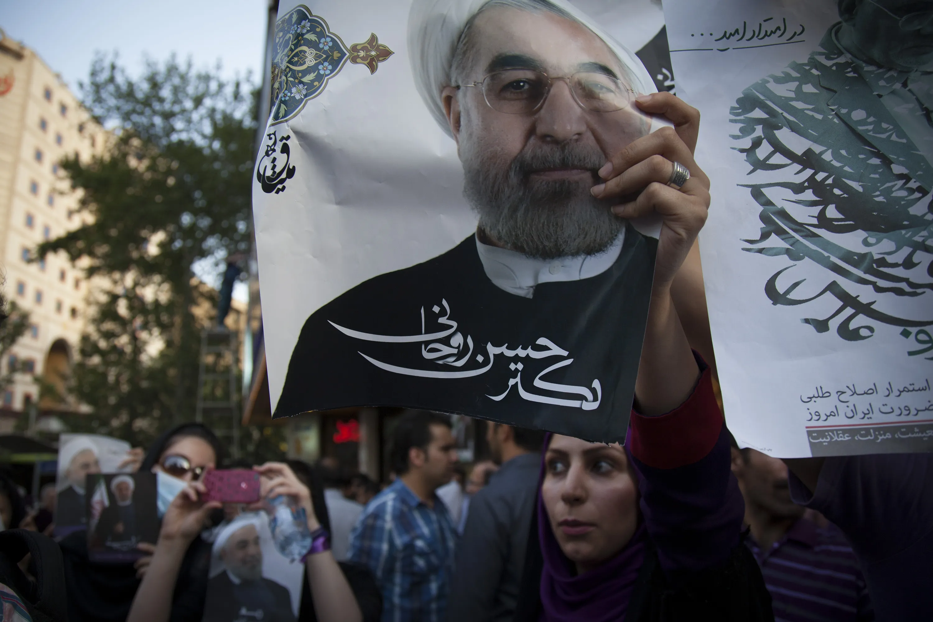 People hold campaign posters of Iranian presidential candidate Hassan Rohani in the streets during a presidential election rally in Tehran, Iran on June 11, 2013. Photographer: Majid Saeedi/Getty Images