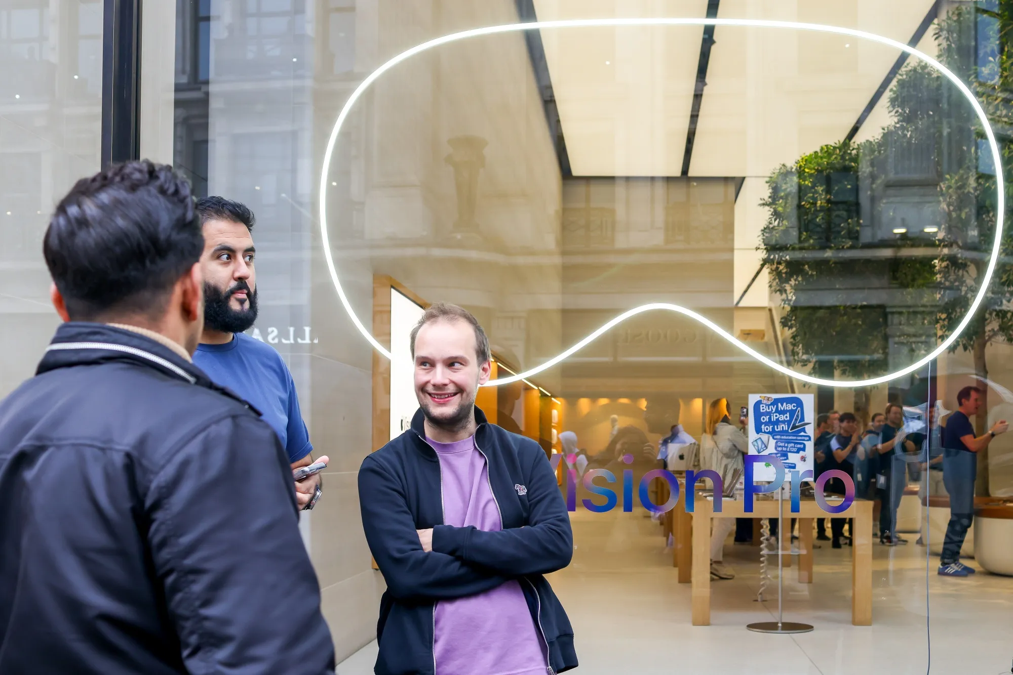 Customers wait outside an the Apple store with a Vision Pro advertisement.