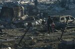 A man walks his dog past burnt out vehicles and debris following a missile attack on the Retroville shopping mall in Kyiv on March 21, 2022.  
