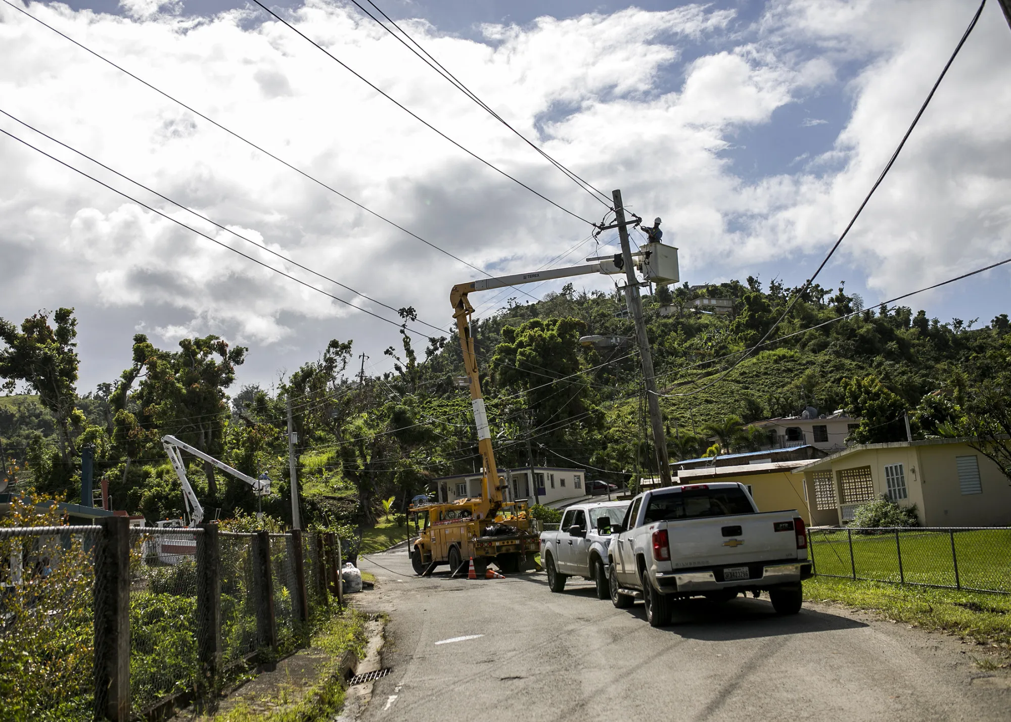 A worker stands in a cherry picker while fixing power lines on a utility pole in Yabucoa, Puerto Rico, on May 18, 2018.