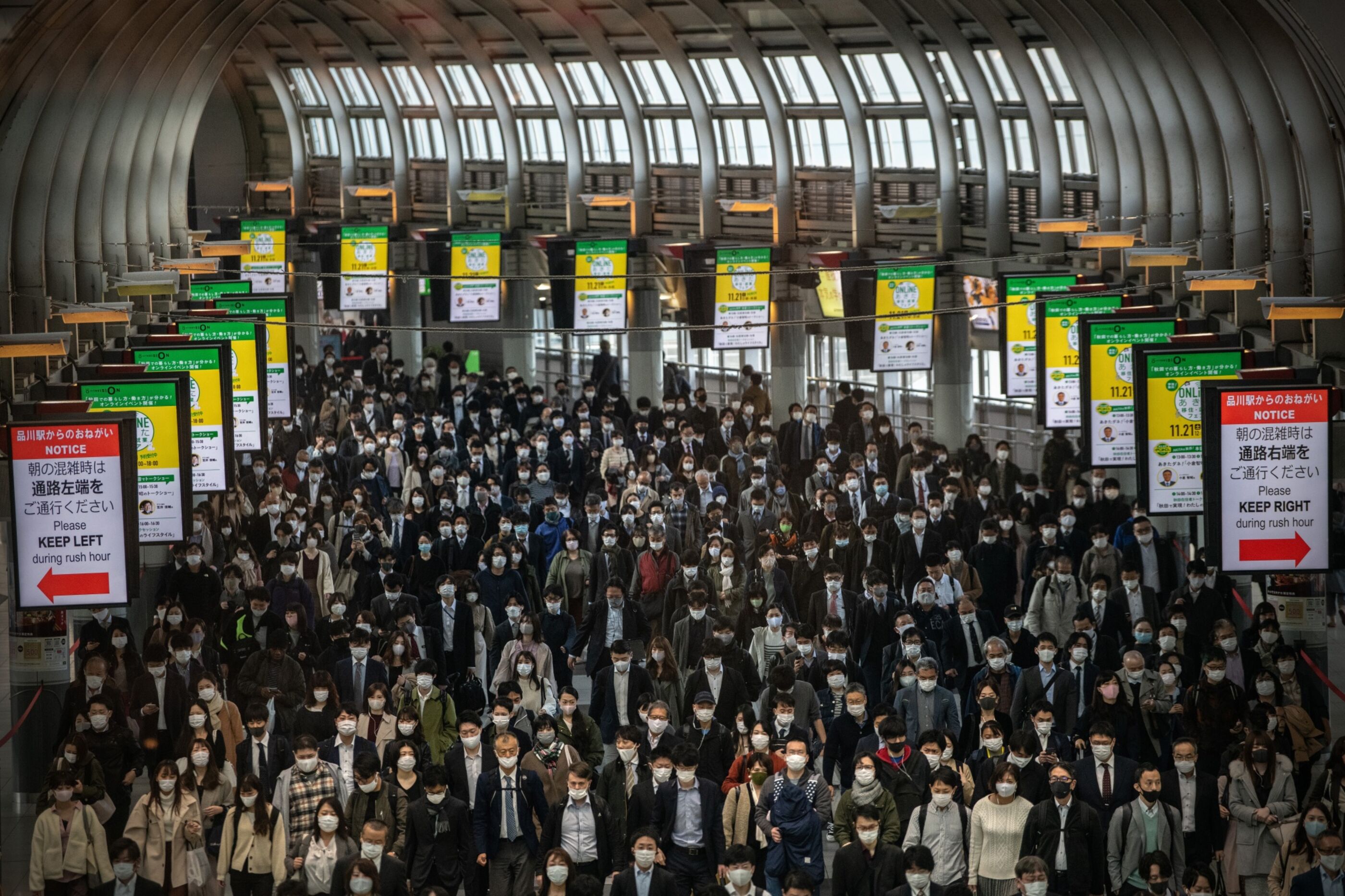A large crowd of commuters wearing masks as they walk through Shinagawa station in Tokyo