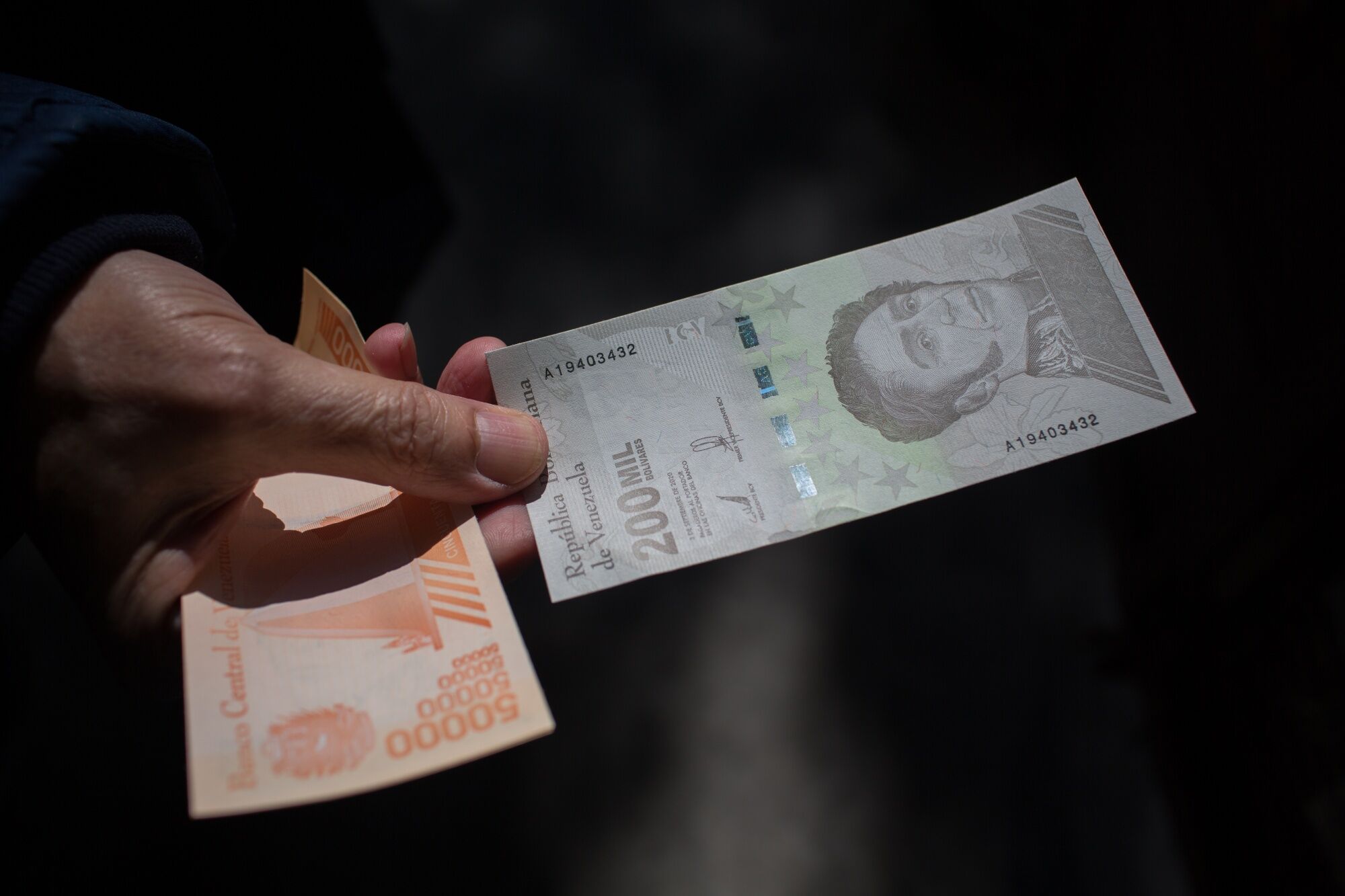 A person holds a 200,000 bolivar banknote outside a bank in Caracas, Venezuela.