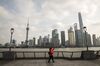 A pedestrian uses a smartphone while walking along the Bund as skyscrapers of the Pudong Lujiazui Financial District stand across the Huangpu River in Shanghai, China, on Friday, Dec. 28, 2018. China announced plans to rein in the expansion of lending by the nation's regional banks to areas beyond their home bases, the latest step policy makers have taken to defend against financial risk in the world's second-biggest economy.