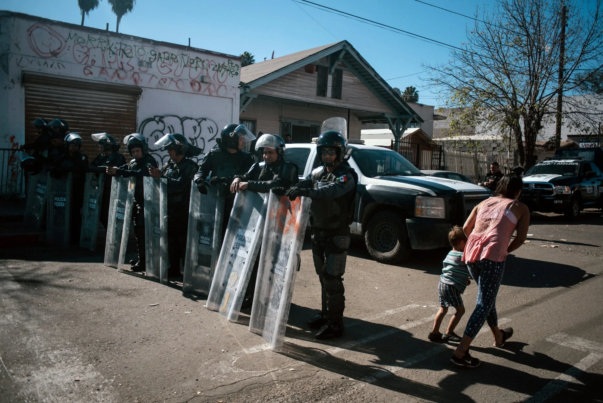 Asylum seekers pass in front of Mexican riot police officers in Tijuana, Mexico, on Nov. 26, 2018.