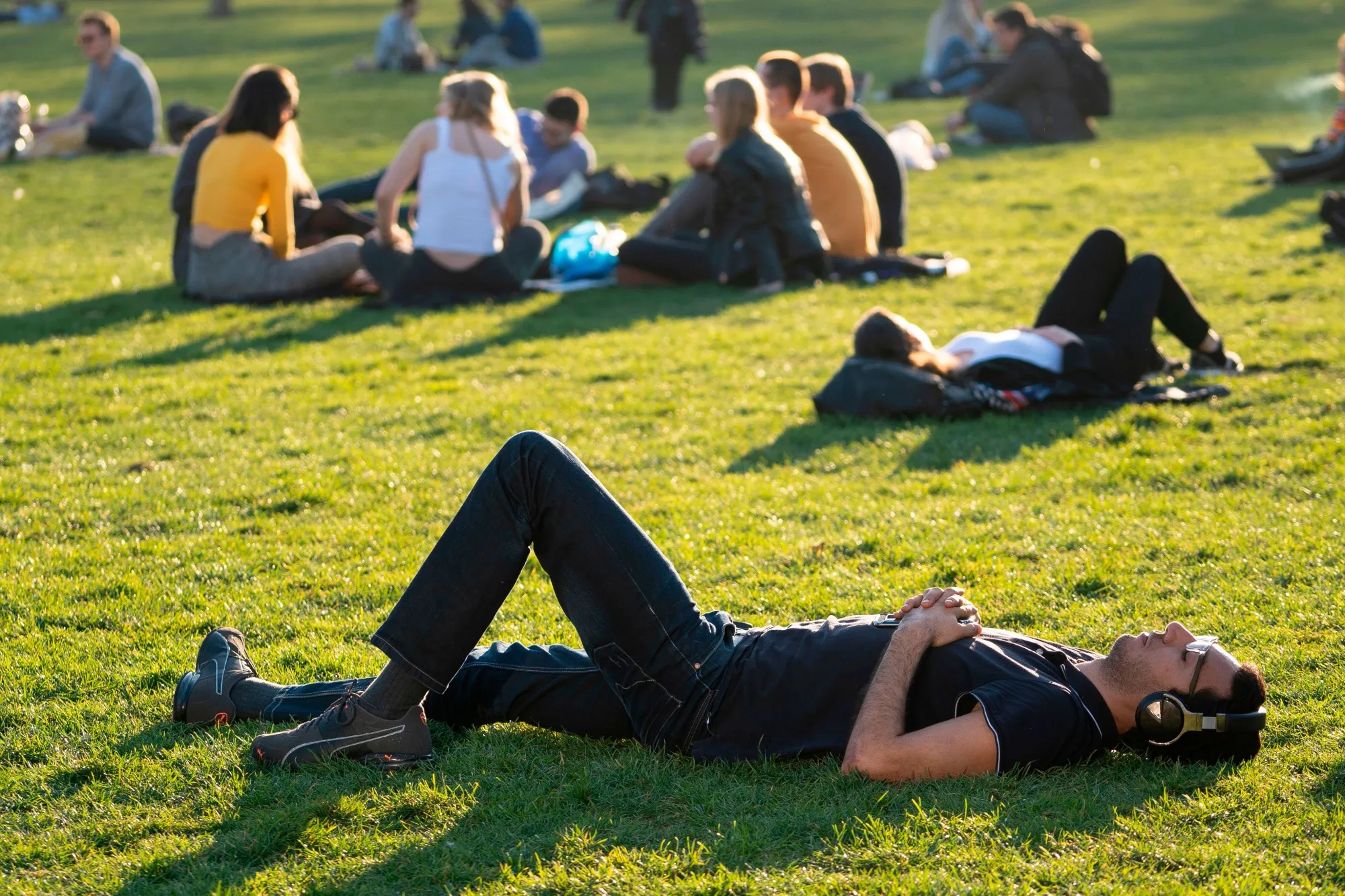 People relax on the grass as the sun shines, in Green Park in central London on February 26, 2019,&nbsp;