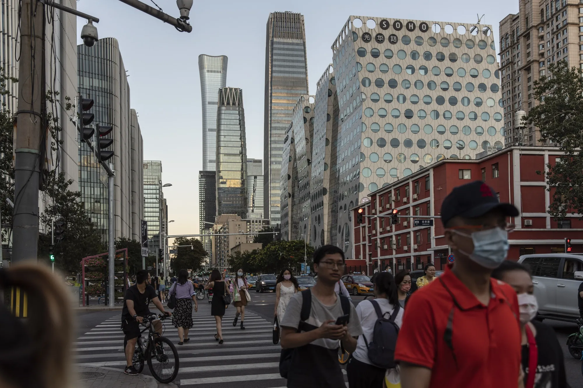 Pedestrians cross a traffic intersection near commercial buildings in Beijing, China.