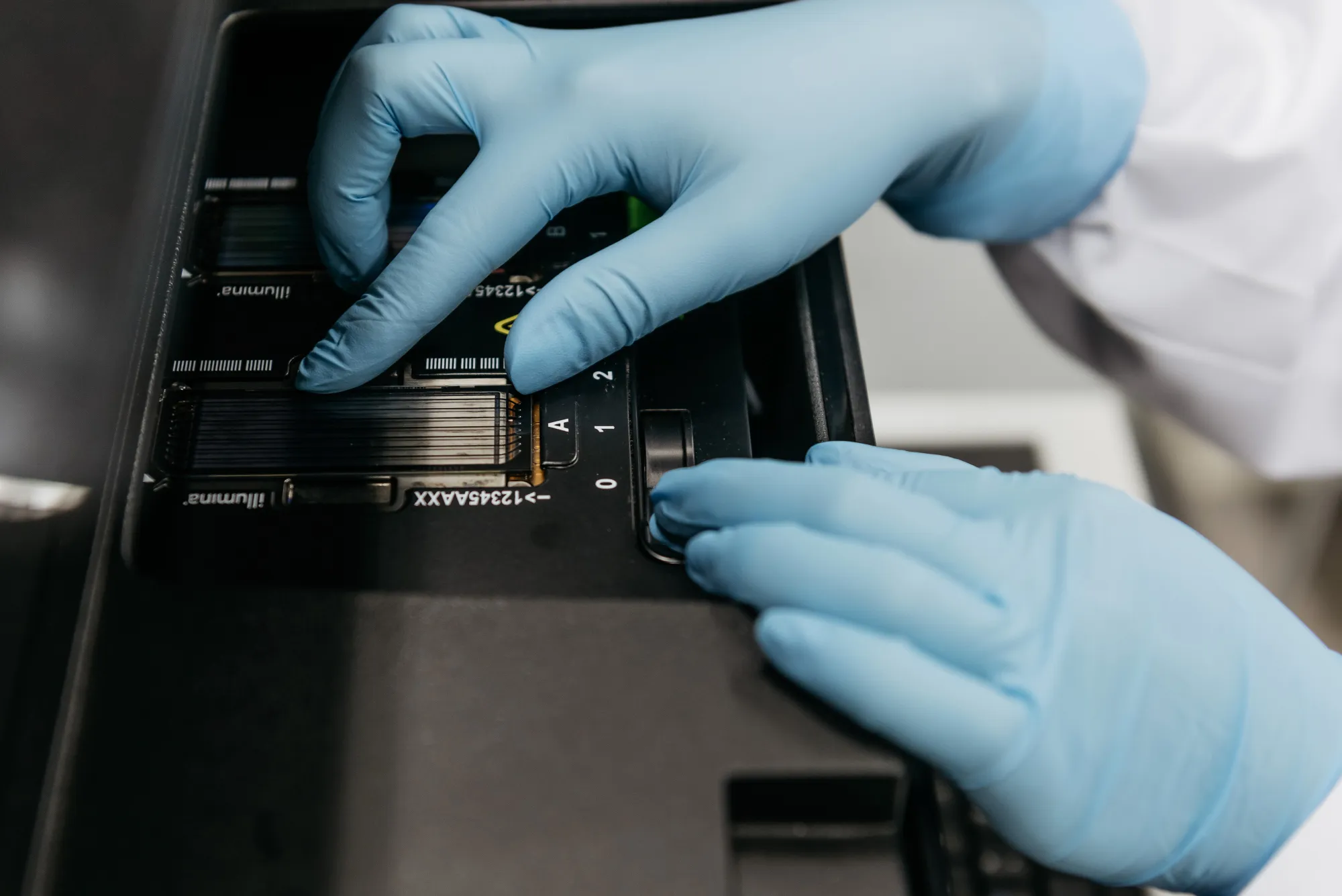 A technician places a flow cell glass slide into an Illumina Inc. DNA sequencing machine.